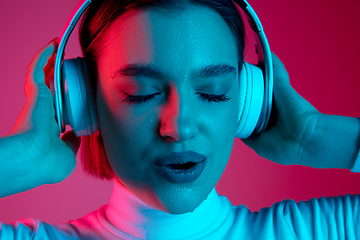 Image showing Caucasian woman\'s portrait isolated on pink studio background in multicolored neon light