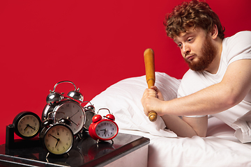 Image showing Man wakes up and he\'s mad at clock ringing, switches it off with baseball bat