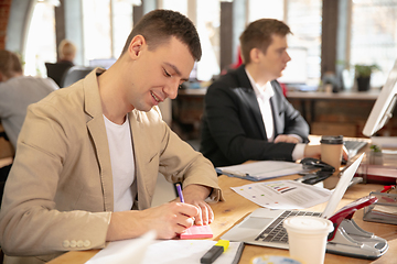 Image showing Young caucasian colleagues working together in a office using modern devices and gadgets