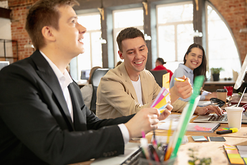 Image showing Young caucasian colleagues working together in a office using modern devices and gadgets