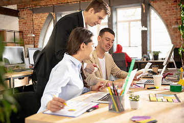 Image showing Young caucasian colleagues working together in a office using modern devices and gadgets