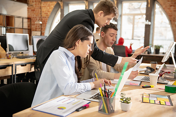 Image showing Young caucasian colleagues working together in a office using modern devices and gadgets