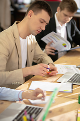 Image showing Young caucasian colleagues working together in a office using modern devices and gadgets