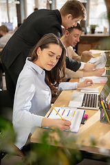 Image showing Young caucasian colleagues working together in a office using modern devices and gadgets