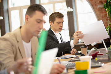 Image showing Young caucasian colleagues working together in a office using modern devices and gadgets