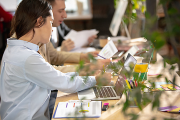 Image showing Young caucasian colleagues working together in a office using modern devices and gadgets