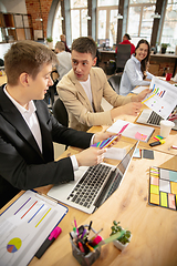 Image showing Young caucasian colleagues working together in a office using modern devices and gadgets