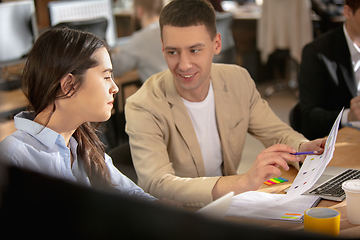 Image showing Young caucasian colleagues working together in a office using modern devices and gadgets