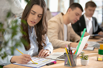 Image showing Young caucasian colleagues working together in a office using modern devices and gadgets