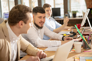 Image showing Young caucasian colleagues working together in a office using modern devices and gadgets