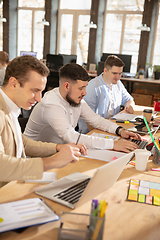 Image showing Young caucasian colleagues working together in a office using modern devices and gadgets