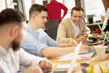 Image showing Young caucasian colleagues working together in a office using modern devices and gadgets