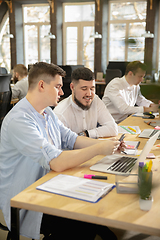 Image showing Young caucasian colleagues working together in a office using modern devices and gadgets