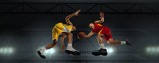 Image showing Young basketball players in competitive fight, motion in flight on black background, look from the bottom. Concept of sport, movement, energy and dynamic.