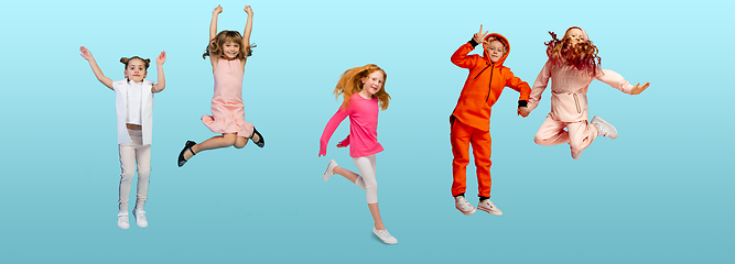 Image showing Group of elementary school kids or pupils jumping in colorful casual clothes on blue studio background. Creative collage.