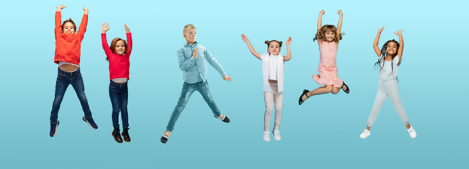 Image showing Group of elementary school kids or pupils jumping in colorful casual clothes on blue studio background. Creative collage.