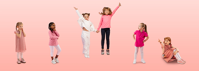 Image showing Group of elementary school kids or pupils jumping in colorful casual clothes on pink studio background. Creative collage.