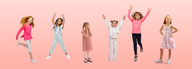 Image showing Group of elementary school kids or pupils jumping in colorful casual clothes on pink studio background. Creative collage.