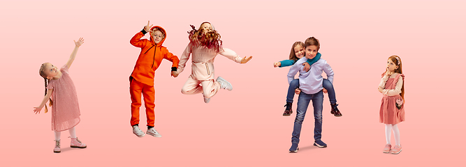 Image showing Group of elementary school kids or pupils jumping in colorful casual clothes on pink studio background. Creative collage.