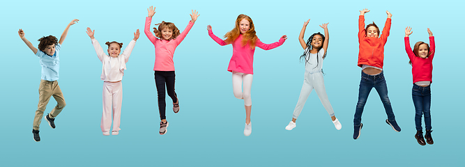 Image showing Group of elementary school kids or pupils jumping in colorful casual clothes on blue studio background. Creative collage.