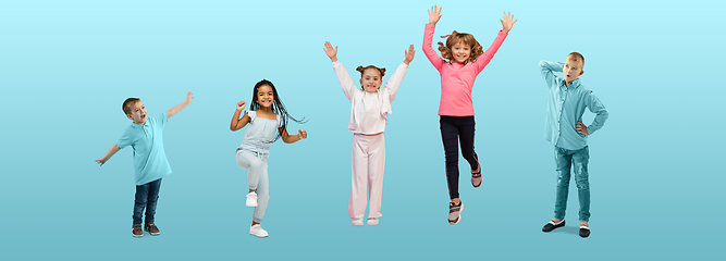 Image showing Group of elementary school kids or pupils jumping in colorful casual clothes on blue studio background. Creative collage.