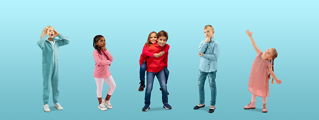 Image showing Group of elementary school kids or pupils dreaming in colorful casual clothes on blue studio background. Creative collage.
