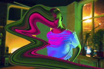 Image showing Portrait of stylish woman in neon lighted interior. The face is smeared, sucked into the screen. The concept of social network dependency