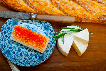 Image showing French cheese and fresh  baguette on a wood cutter