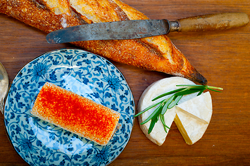 Image showing French cheese and fresh  baguette on a wood cutter