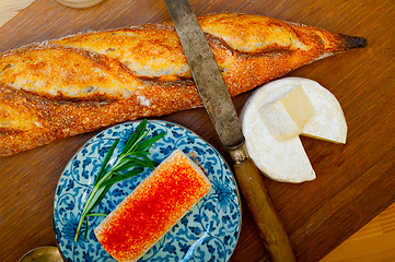 Image showing French cheese and fresh  baguette on a wood cutter