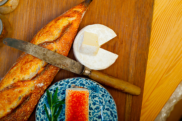 Image showing French cheese and fresh  baguette on a wood cutter