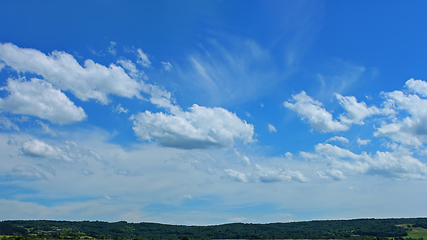 Image showing Beautiful cloudscape over a wooded hilly countryside in fine sum