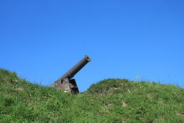 Image showing Old black cannon in wooden base on green grass hill on the backg