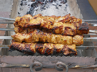 Image showing Meat strung on metal skewers fried on charcoal outdoors