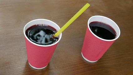 Image showing Two pink paper cups with a drink standing on a lacquered wooden 