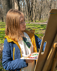 Image showing Beautiful young girl painted on an easel in park