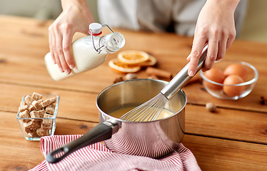 Image showing hands with whisk and milk cooking eggnog