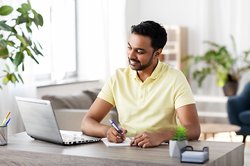 Image showing indian man with notebook and laptop at home office