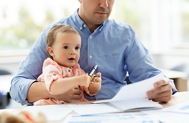 Image showing father with baby working at home office