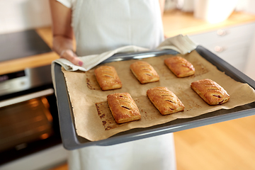 Image showing woman holding baking tray with pies at kitchen