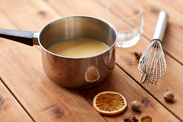 Image showing pot with eggnog, whisk and spices on wood