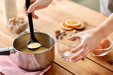 Image showing hands with ladle pouring eggnog from pot to glass