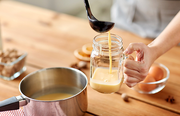 Image showing hands with ladle pouring eggnog from pot to glass
