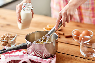 Image showing hands with whisk and milk cooking eggnog