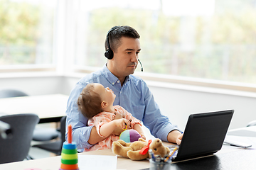 Image showing father with baby working on laptop at home office