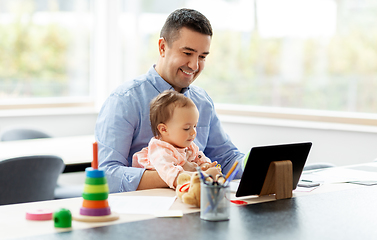 Image showing father with baby working on tablet pc at home