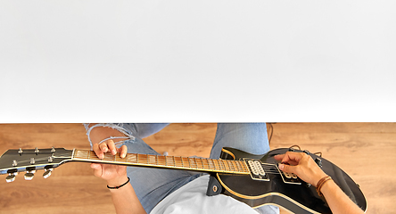 Image showing young man playing guitar sitting at table