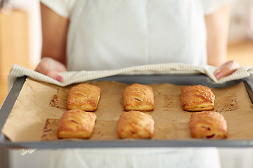 Image showing woman holding baking tray with pies at kitchen