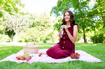 Image showing happy woman with picnic basket and drink at park