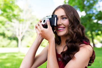 Image showing happy woman with camera photographing at park